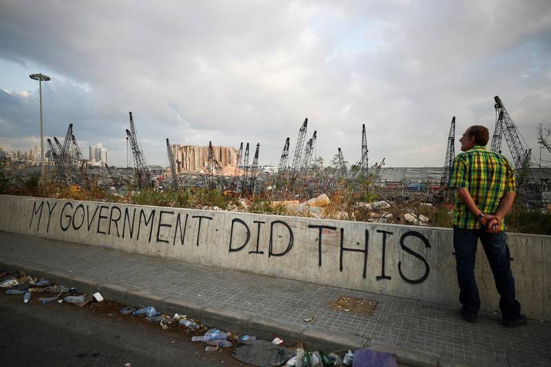 A man stands next to graffiti at the damaged port area in the aftermath of a massive explosion in Beirut, Lebanon August 11, 2020. REUTERS/Hannah McKay     TPX IMAGES OF THE DAY