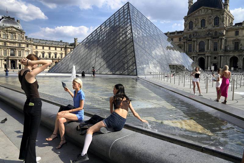 Visitors take a break outside the Louvre Museum courtyard, in Paris, Wednesday, June 9, 2021. France is back in business as a tourist destination after opening its borders Wednesday to foreign visitors who are inoculated against the coronavirus with vaccines approved by the European Union's medicines agency. France's acceptance of only the Pfizer, Moderna, AstraZeneca and Johnson & Johnson vaccines means that tourism is still barred for would-be visitors from China and other countries that use other vaccines. (AP Photo/Francois Mori)