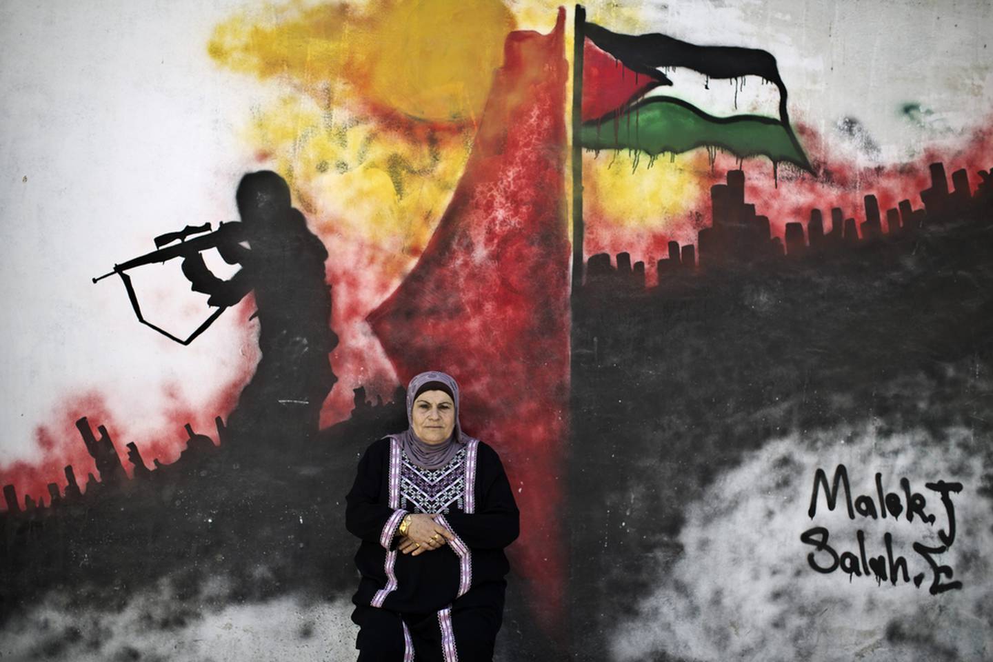 Palestinian refugee Layla Afaneh, 67, in front of a mural at a refugee camp in Ramallah. She was 18 months old when her family were forced to leave their village of Barfeelia, near the central Israeli town of Ramla, in 1948. 