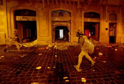 Lebanese army soldiers run past a damaged Alfa shop during a protest against a ruling elite accused of steering Lebanon towards an economic crisis in Beirut. REUTERS