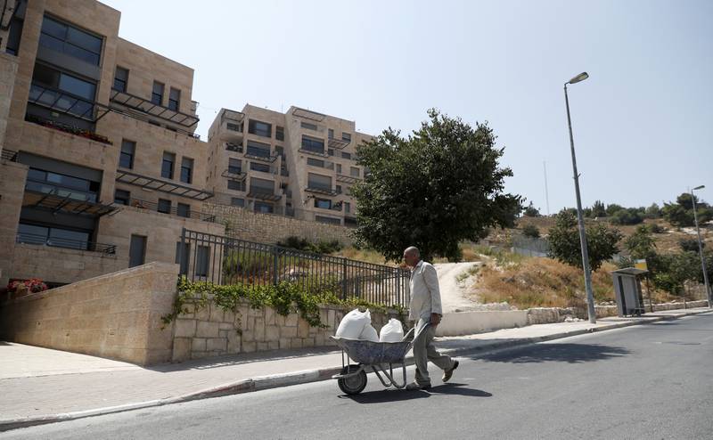 A picture taken on September 10, 2017 from Jabel Mukaber, a Palestinian neighbourhood In Israeli-occupied East Jerusalem, shows a worker pushing a cart in the Israeli settlement of Nof Zion.
