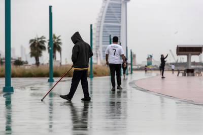 DUBAI, UNITED ARAB EMIRATES. 10 JANUARY 2020. Heavy rains in Dubai during the night had residenst wake up to wet pavements and large water puddles with some areas experiencng mild flooding. A man sweeps water on from the running track along Kite Beach. (Photo: Antonie Robertson/The National) Journalist: Standalone. Section: National.