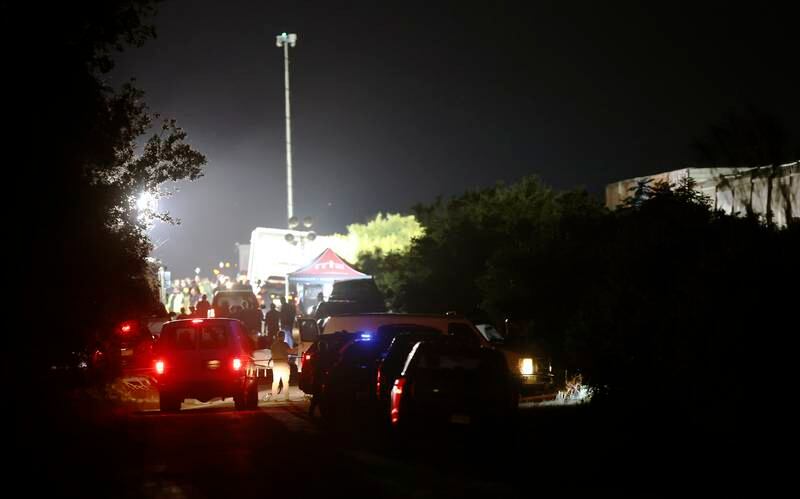 Police and officials man a roadblock near a lorry on the side of the road leading to the location where about 50 migrants were reportedly found dead. EPA
