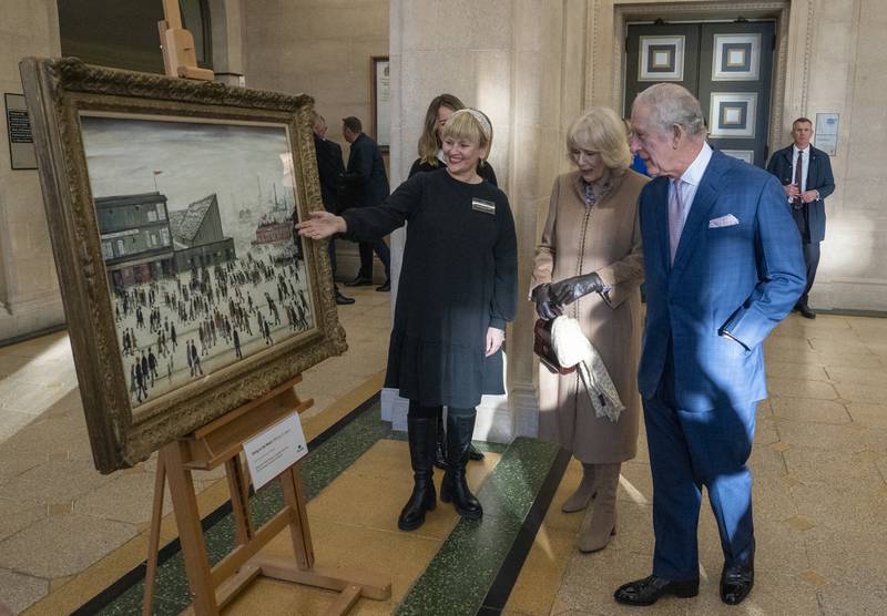 King Charles III and the Queen Consort views L S Lowry's Going to the Match painting during a visit to Bolton Town Hall.