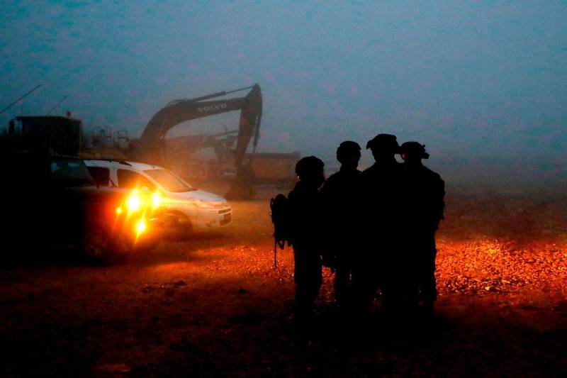 TOPSHOT - Israeli soldiers gather near excavation equipment at work on border with Lebanon, near the northern Israeli town of Metula on December 19, 2018. Israeli Prime Minister Benjamin Netanyahu urged the UN Security Council on December 19 to condemn the Iranian-backed Lebanese shiite movement Hezbollah for digging cross-border "attack tunnels", and to demand that Lebanon prevent such activity from its territory. The Israeli army had announced on December 4 an operation dubbed "Northern Shield" to destroy the tunnels. / AFP / JACK GUEZ
