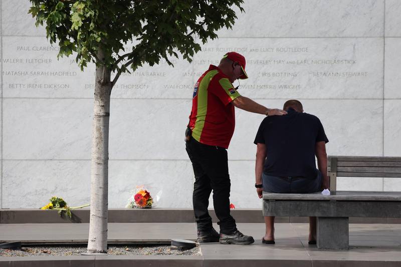 A security guard comforts a family member who lost a loved as he sits in front of the memorial wall where the names of the 185 killed are inscribed during the national memorial service. Getty Images