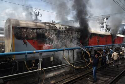 Indian railway workers try to douse the flames after protesters set a passenger train on fire in Secunderabad, Andhra Pradesh. Reuters