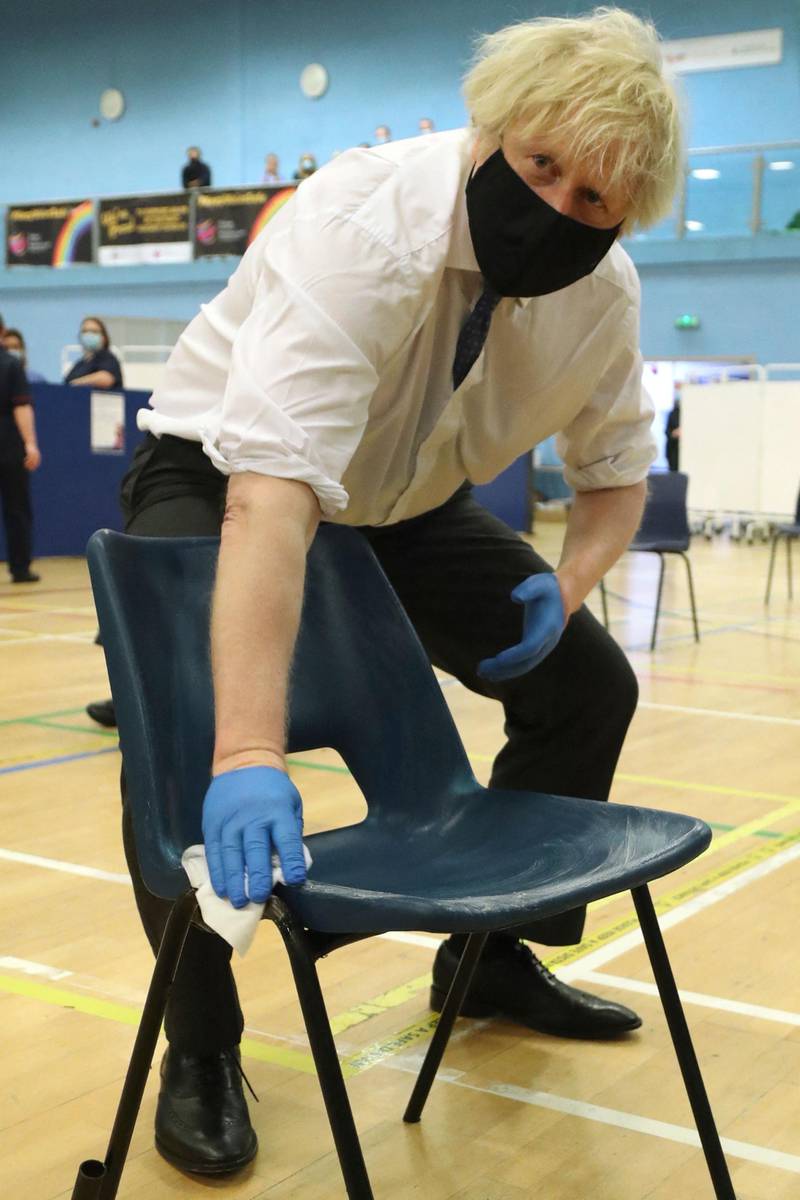 Boris Johnson disinfects a chair in the public waiting area of the vaccination centre at Cwmbran Stadium. AFP