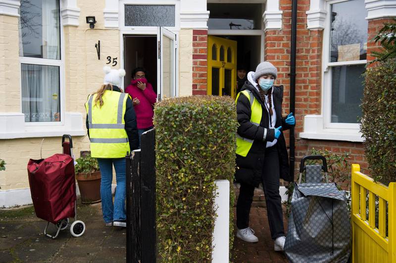 Members of staff speak to residents as they carry out mobile door-to-door virus testing to assess the prevalence of the South African Covid-19 variant in the Ealing district of London. AP Photo