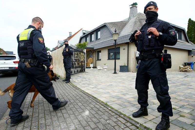 A German police officer and his sniffing dog enter the yard of a villa following a police raid in the clan milieu, in Leverkusen, Germany, June 8, 2021.  REUTERS/Thilo Schmuelgen