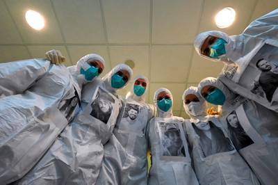Medical workers of the Covid-19 intensive care unit at the Santo Stefano hospital in Prato, near Florence, Tuscany, pose wearing their PPE with photos of themselves printed on it, on December 17, 2020 at the hospital in Prato.   AFP