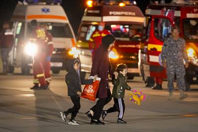A woman and two children evacuated from Gaza walk on the tarmac at the Baza 90 air force base in Otopeni, Romania, after arriving from Egypt. AP