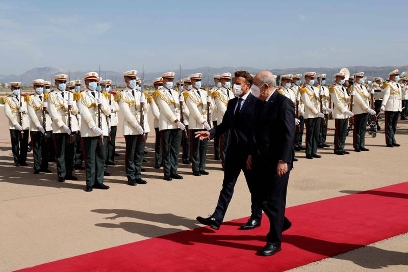 Mr Macron and Mr Tebboune review a guard of honour at Algiers International Airport. AFP