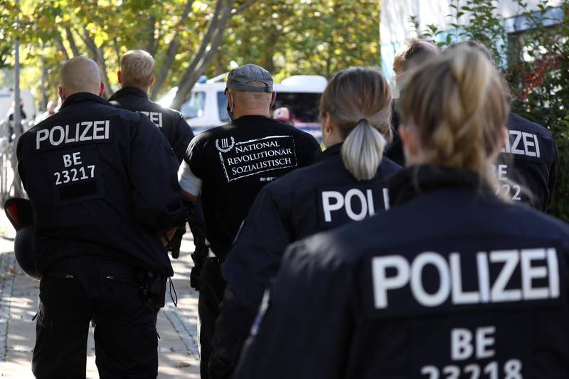 A protestor is detained by police officers during a demonstration of the far-right party The Third Path (Der III. Weg) in Berlin, Germany, October 3, 2020. REUTERS/Christian Mang