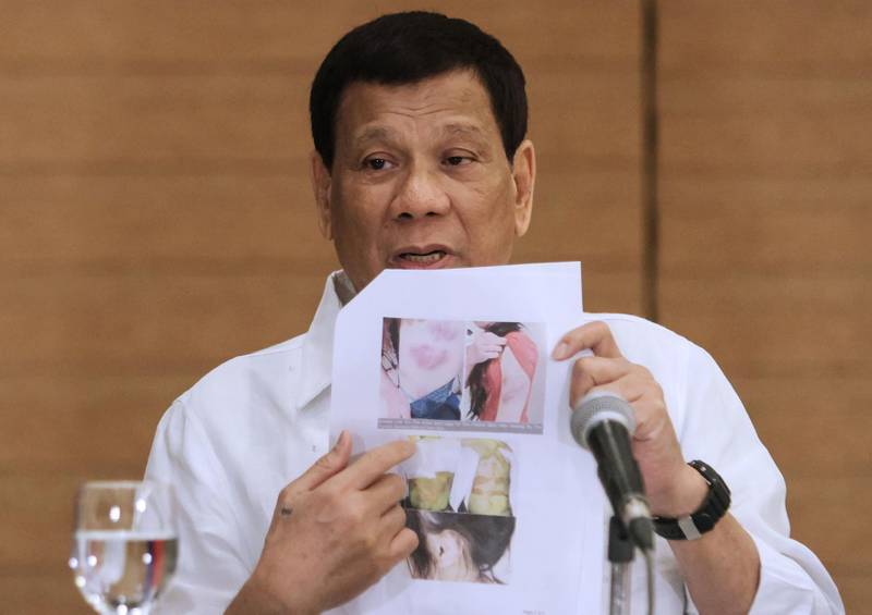 Philippine President Rodrigo Duterte shows a photo of a Filipina worker in Kuwait, of whom he said she had been "roasted like a pig", during a press conference in Davao City, in the southern island of Mindanao on February 9, 2018.
Duterte on February 9, declared himself beyond the jurisdiction of an International Criminal Court probe into thousands of deaths in his "drugs war", claiming local laws do not specifically ban extrajudicial killings. / AFP PHOTO / MANMAN DEJETO