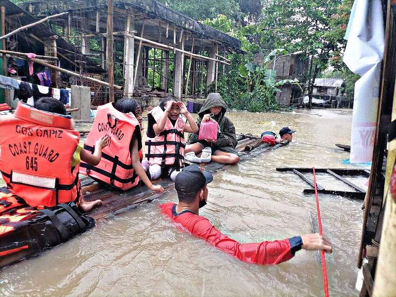 Coast guard personnel evacuate flooded homes on a makeshift raft in Panitan, Capiz province as heavy rain brought on by a tropical storm inundated parts of the Philippines. AFP
