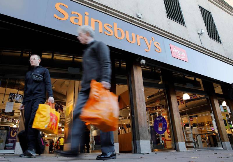 (FILES) In this file photo taken on November 07, 2019 shoppers walk past a Sainsbury's and Argos sign above the entrance to a Sainsbury's supermarket store in London. Sainsbury has announced 3,500 job cuts on November 5, 2020 mainly from the Argos chain it bought in 2016. / AFP / Tolga AKMEN
