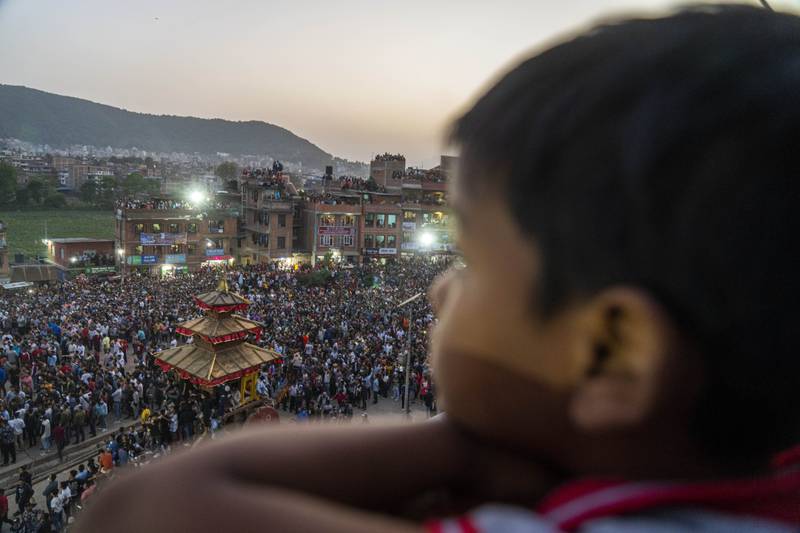 A Nepalese boy watches devotees pull down the "lingo" a long wooden pole symbolising a phallus during Biska Jatra festival in Bhaktapur, Nepal, Thursday, April 14, 2022.  During this festival, also regarded as Nepalese New Year, images of Hindu god Bhairava and his female counterpart Bhadrakali are enshrined in two large chariots and pulled to an open square after which rituals and festivities are performed.  (AP Photo / Niranjan Shrestha)