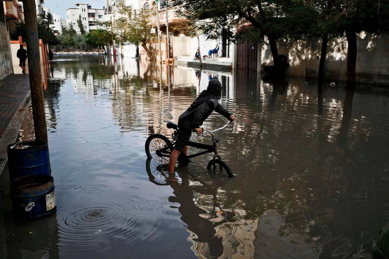 A Palestinian child rides a bicycle through a street flooded by rainwater in Gaza City. AFP