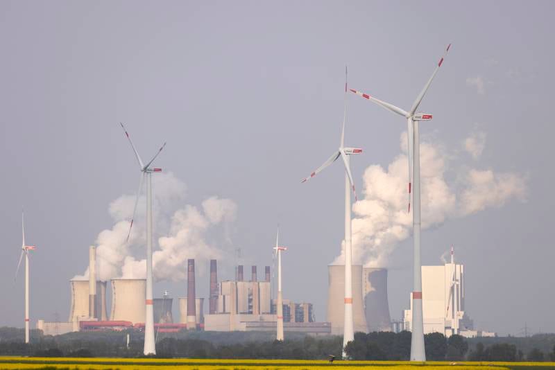 Wind turbines spin as steam rises from a coal-fired power plant near Bedburg, Germany. Getty