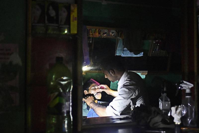 A customer gets a shave at a barber shop illuminated by the torch function of a mobile phone at night in a village on the outskirts of Alwar, Rajasthan, India, on Tuesday, April 17, 2018. Rural electrification is a cornerstone of the Indian Prime Minister Narendra Modi's plan to improve the lives of Indians, a plan which included connecting more than 18,000 villages by the end of this month. With only a few left to be electrified, according to government data, that's a target Modi's administration looks set to meet. But that will still keep almost 32 million homes in the dark: the government deems a village “electrified” if 10 percent of its households, as well as public places such as schools and health centers, are connected. Photographer: Anindito Mukherjee/Bloomberg