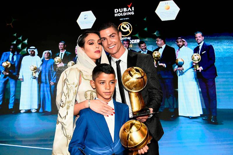 Cristiano Ronaldo (C), holding his "Best Player of the Year 2018 Award" poses his companion Georgina Rodriguez (L) and his son Cristiano Jr, holding his father's "433 Fans' Award", during the 10th edition of the Dubai Globe Soccer Awards. AFP