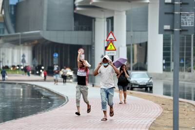 Pedestrians run for cover as rain falls on New Year's Eve in Dubai. City residents were woken by thunder and lightning in the early hours