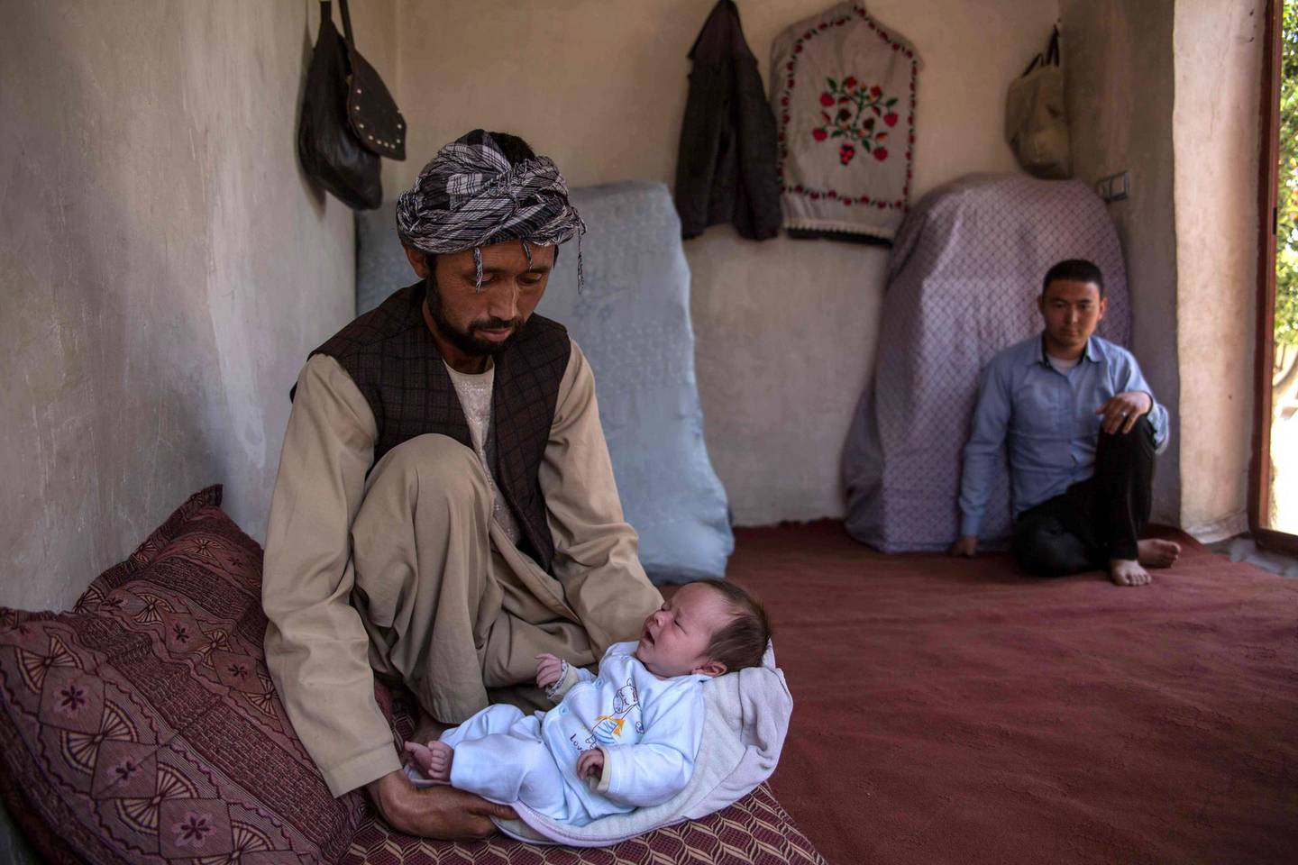 Ahmed Reza, 34, holds his son Abbas at his home in the western outskirts of Kabul, a place of relative calm and safety. His wife Rokaia has been brutally killed in the attack on the maternity ward in Dasht-e-Barchi. 