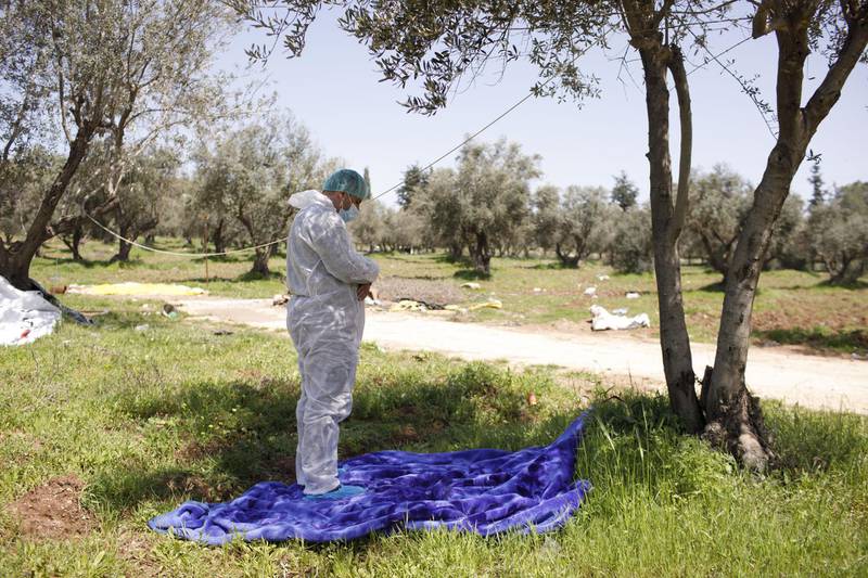 A municipal worker wearing a hazmat overall prays during a break in disinfecting duties for Palestinian workers at the Tarqumya checkpoint in Hebron, West Bank. Bloomberg