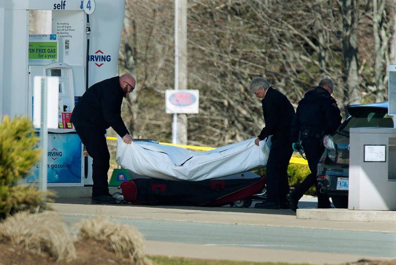 Workers with the medical examiner's office remove a body from a gas station in Enfield, Nova Scotia.  AP