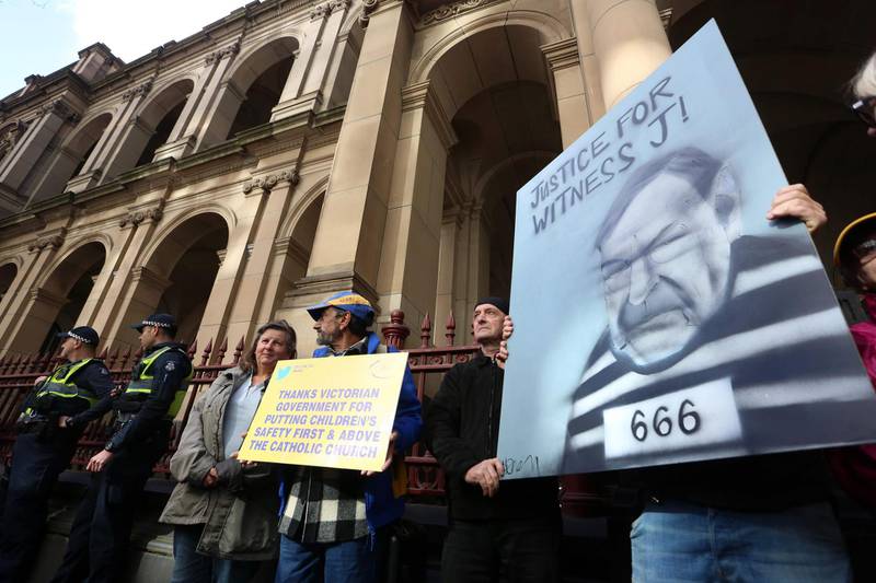 TOPSHOT - Protestors holding placards outside the court building as Australian Cardinal George Pell is escorted into the Supreme Court of Victoria in Melbourne on August 21, 2019. Convicted paedophile cardinal George Pell had his appeal against child sex abuse charges rejected by an Australian court on Wednesday, August 20, 2019. / AFP / Asanka Brendon RATNAYAKE
