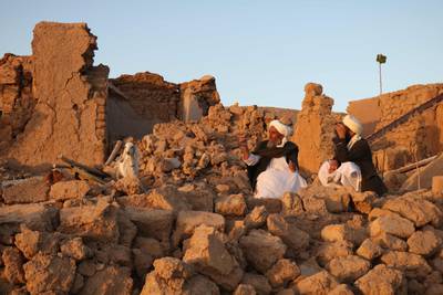 Afghan residents sit at a damaged house after the earthquake. AFP