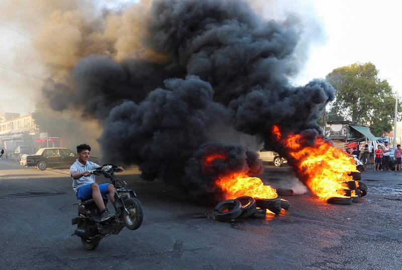 A young man boy rides his motorbike near burning tires during a sit-in protest against the fall in pound currency and mounting economic hardship, in Ghazieh. Reuters