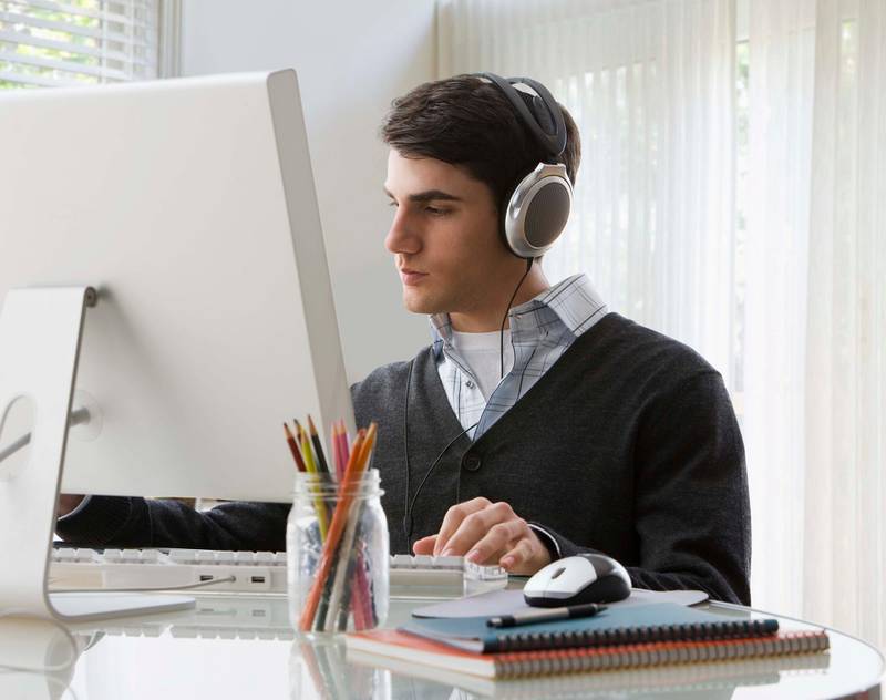 Young man working at computer with headphones on. Getty Images