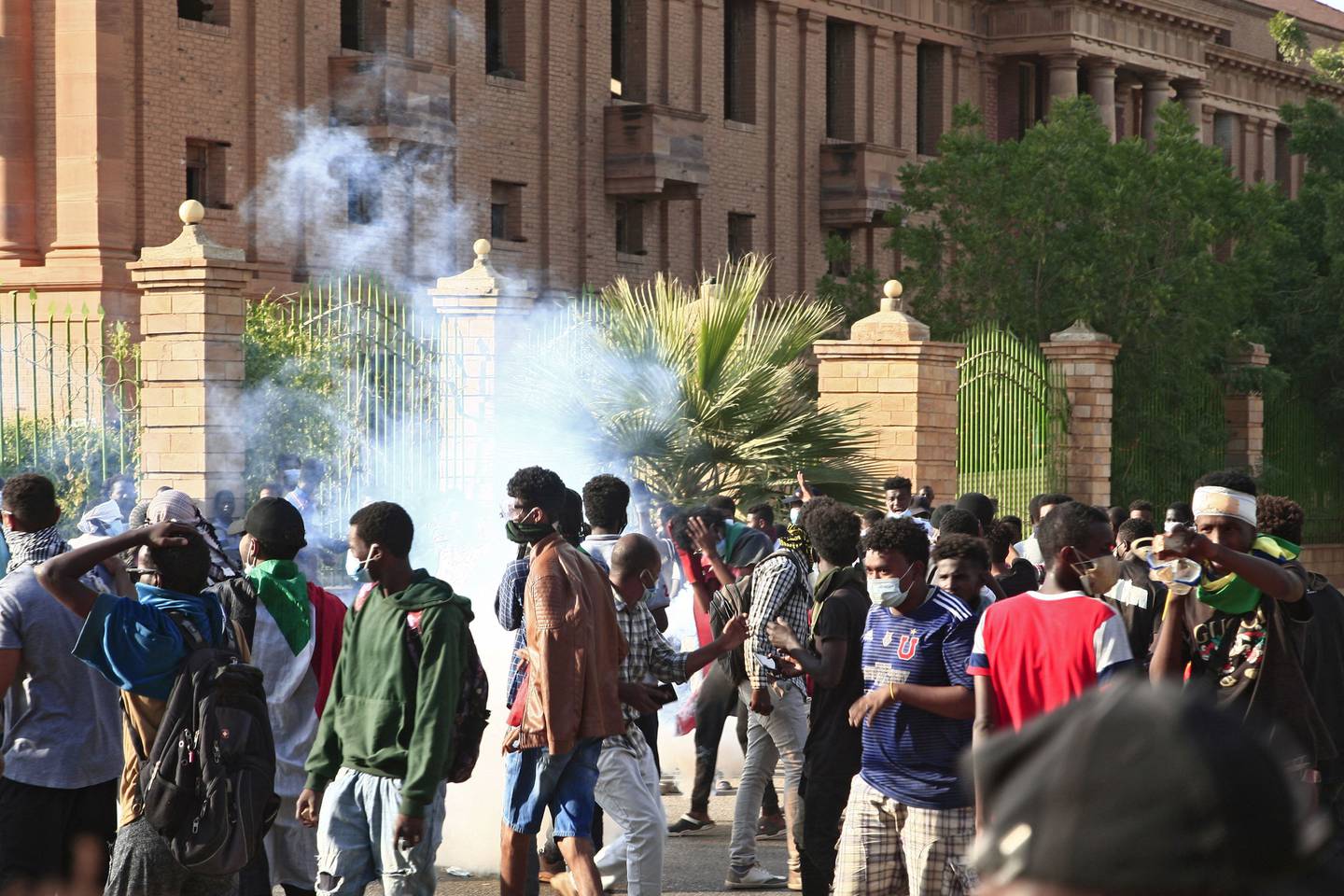 Sudanese protesters scatter from tear gas fired by security forces near the presidential palace in Khartoum during a rally to mark three years since the start of mass demonstrations that led to the removal of autocrat Omar Al Bashir. AFP 