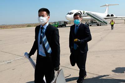 Chinese embassy officials react after the arrival of medical aid at Baghdad Airport in Iraq. AP