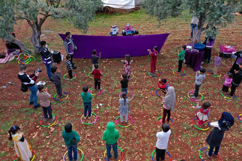 Volunteers from the Violet organisation perform a puppet show for children in a camp for displaced Syrians to inform them about coronavirus and the methods used to limit its spread, in the village of Kafr Yahmul, Idlib, Syria, on April 7, 2020. AFP