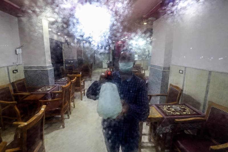 A worker disinfects the door of a cafe in the Egyptian capital Cairo. AFP