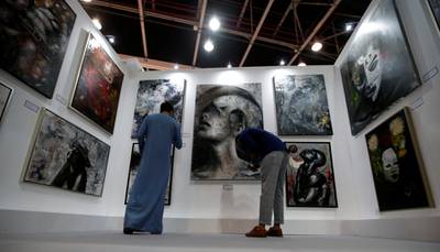 Visitors inspect artworks by the artist Tres Ases from Spain currently living in Dubai at the Dubai World Trade Centre. EPA