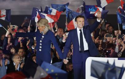 Mr Macron and his wife Brigitte Macron acknowledge the greetings of supporters near the Paris landmark. AFP