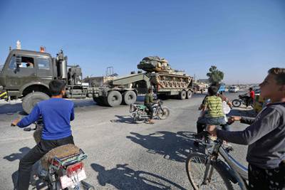 Inhabitants of Maaret Al Numan in Syria's northern province of Idlib watch a convoy of Turkish military vehicles reportedly headed to assist rebels against regime forces.  AFP