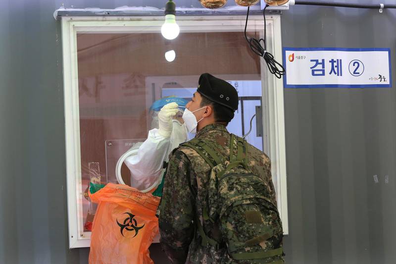 A medical worker takes a nasal sample from a soldier at a coronavirus testing site in Seoul, South Korea. AP