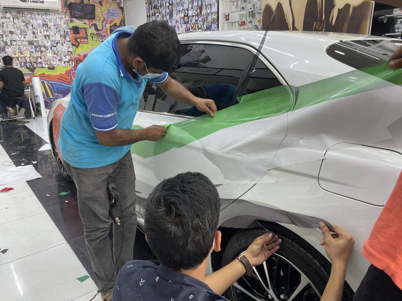 Employees place a large flag on side of car at Tornado car accessories shop in Mussaffah, Abu Dhabi.