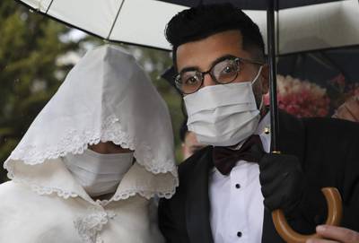 Palestinian groom Imad Sharaf, wearing gloves and a face mask, accompanies his bride Bara'a Amarneh as they arrive at their home in the village of al-Dahriya, south of Hebron in the West Bank. The couple celebrated their wedding wearing masks and gloves as caution measures during the corona virus COVID-19 pandemic. Guests were restricted to be first family. AFP