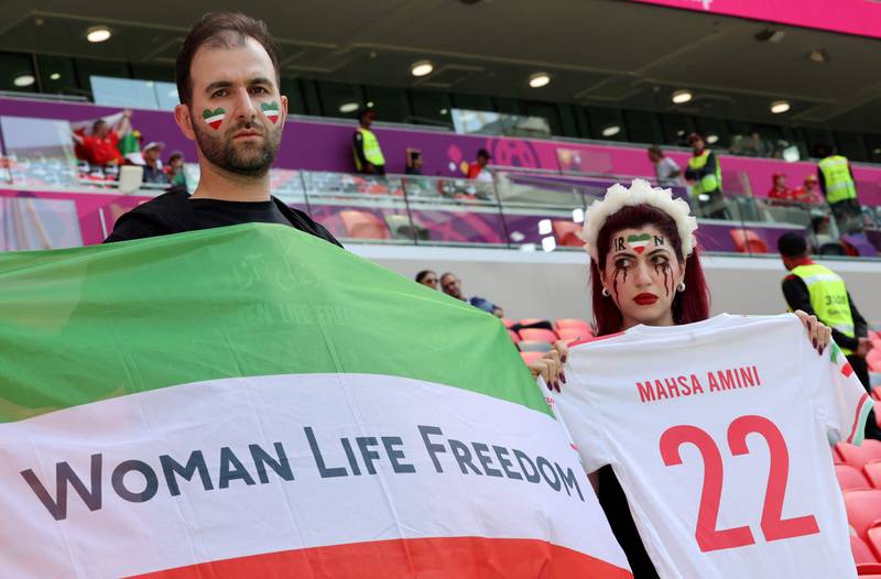 A supporter of Iran's football team, with make-up resembling  bloody tears, holds a football jersey with Amini's name, at the stadium in Doha. AFP
