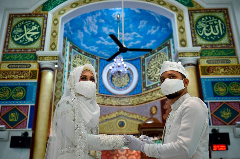 A couple wearing face masks amid the coronavirus pandemic at their wedding ceremony at a mosque in Banda Aceh, Indonesia. AFP