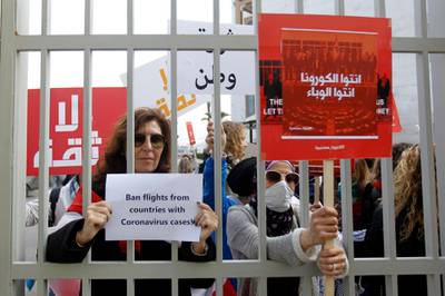 Anti-government protesters carry banners read in Arabic, 'You are the coronavirus, you are the epidemic during a protest in front of the Lebanese Ministry of Health.  EPA