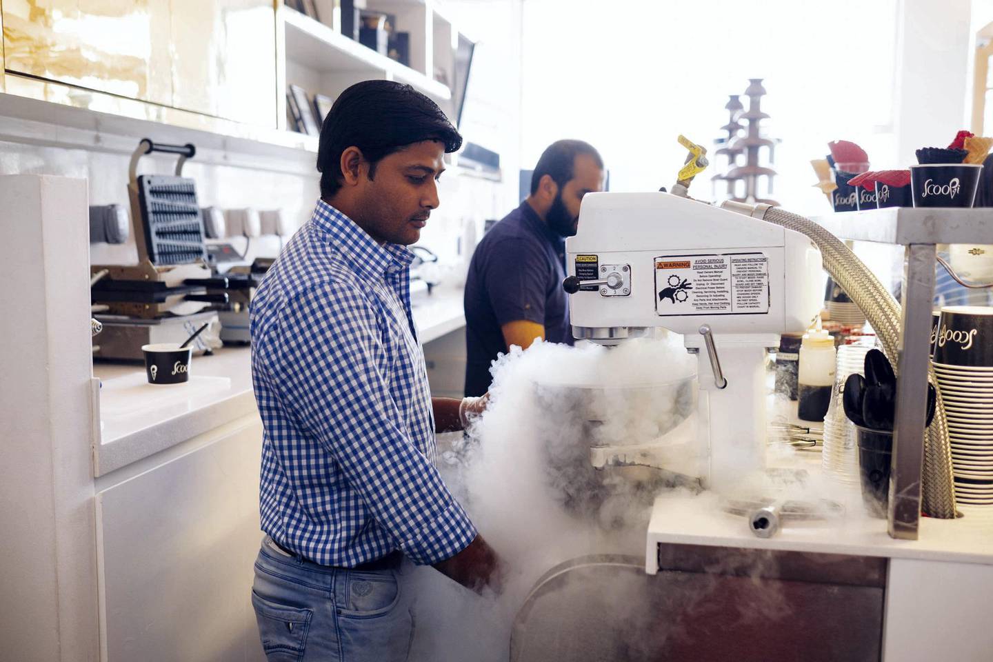 Scoopi Ice cream cafe, Jumeirah Beach road, Dubai. Founded in 2014. Here a member of staff: Azad Sonu prepares an ice cream with the owner Zunin Doshi. Anna Nielsen for the National