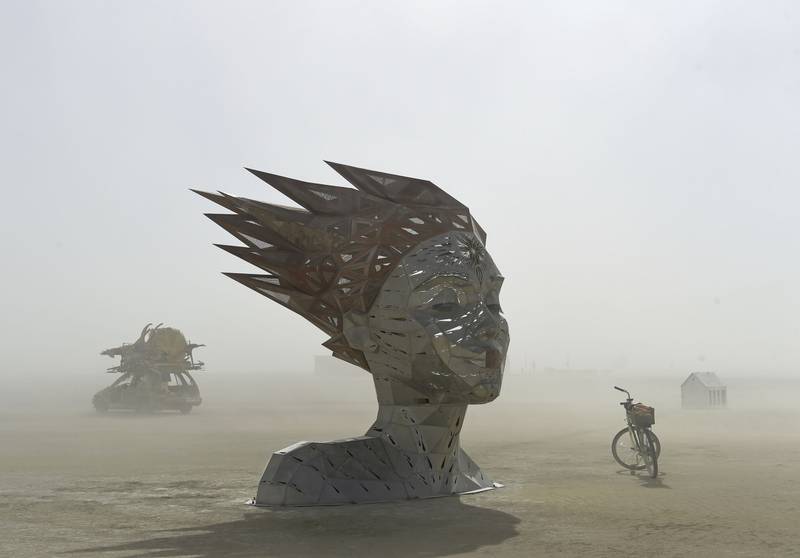 An art car rides past an art piece at Burning Man near Gerlach, Nev.  on Friday, Aug.  26, 2022.  Burning Man returns after a two-year pandemic shutdown.  (Andy Barron / The Reno Gazette-Journal via AP)