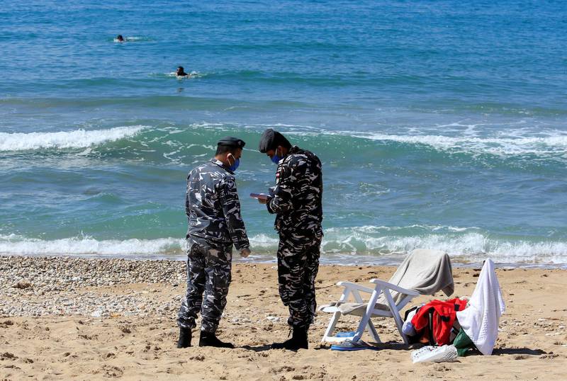 Police officers write a ticket for people swimming at the beach, as Lebanese Prime Minister Hassan Diab asked security forces to enforce stricter measures to keep people indoors and prevent gatherings to curb the coronavirus outbreak, in Sidon, Lebanon. Reuters